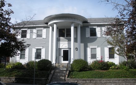 two story gray greek revival house with four columns in front