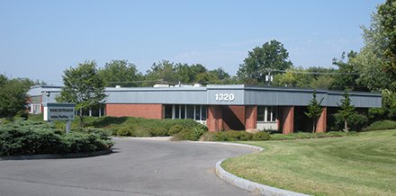 flat red brick office building with gray color toward roof and number 1320 in right corner of building
