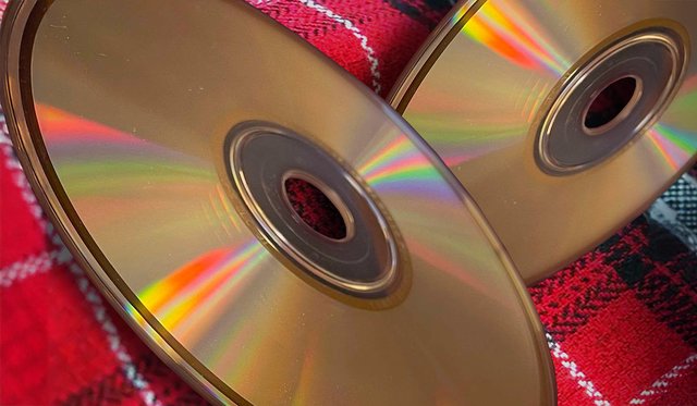 Close up of two CDs placed on a red plaid fabric with white and black stripes