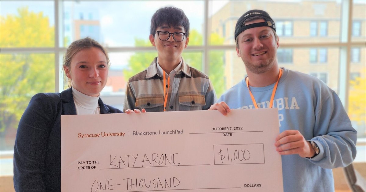2022 Ideas Competition winner Katy Arons, event organizer, Andrew Kim and emcee Selim Dangoor hold an oversized $1,000 check