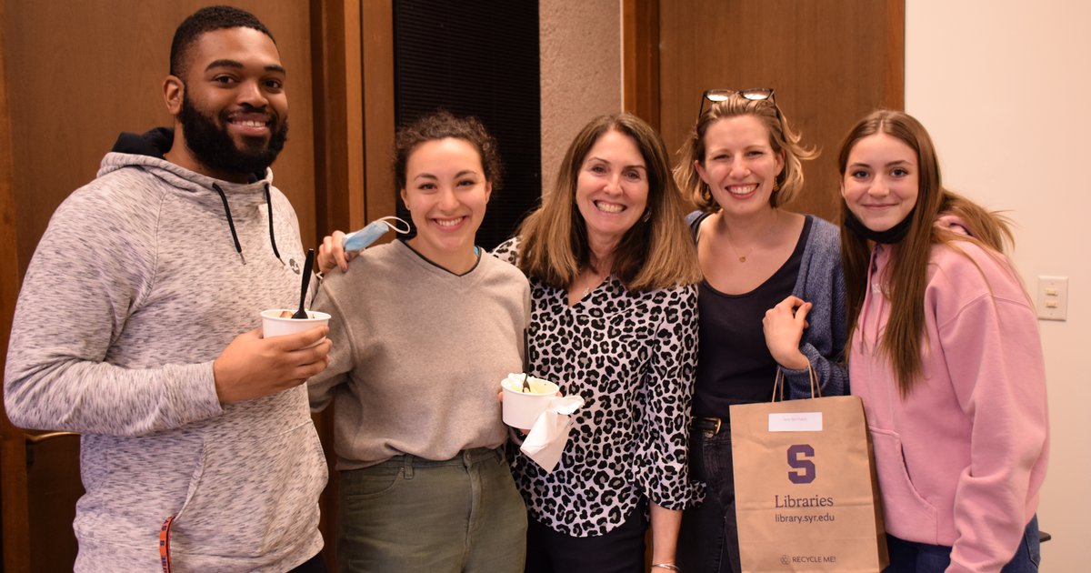 Employees from the Preservation Department posing with their supervisor and holding brown paper bags with Syracuse University Libraries logo