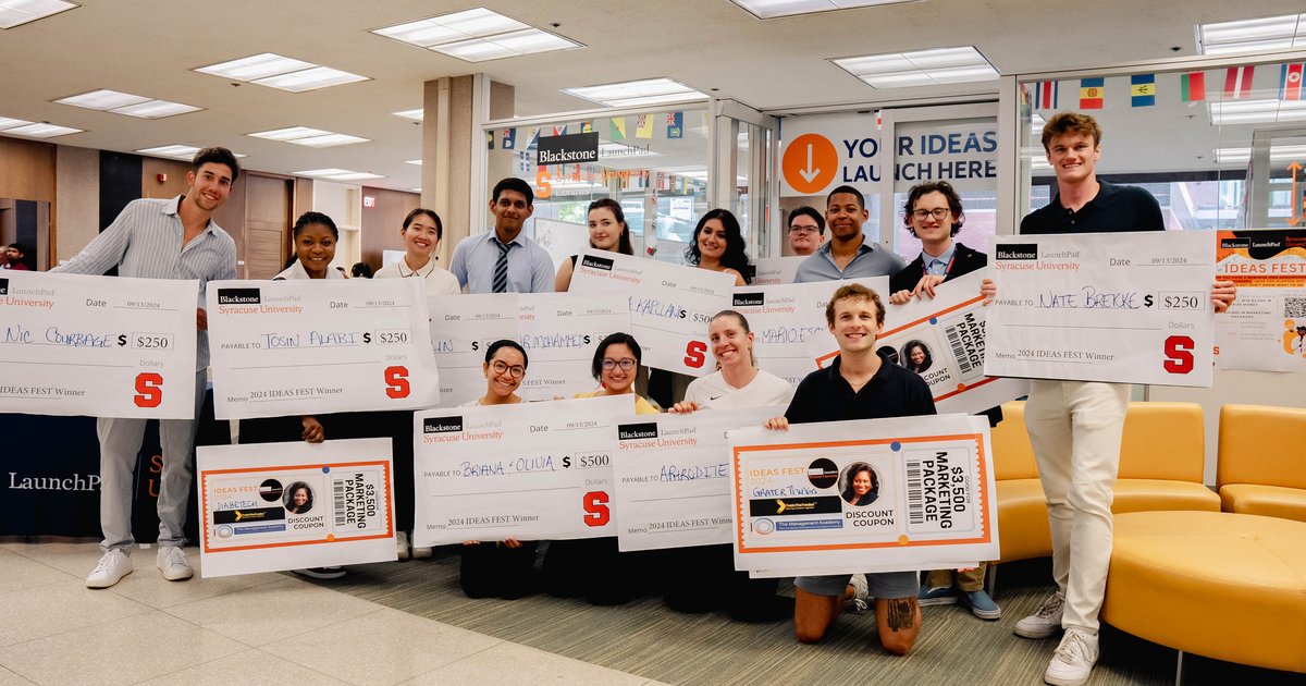 student winners holding up giant checks in front of LaunchPad