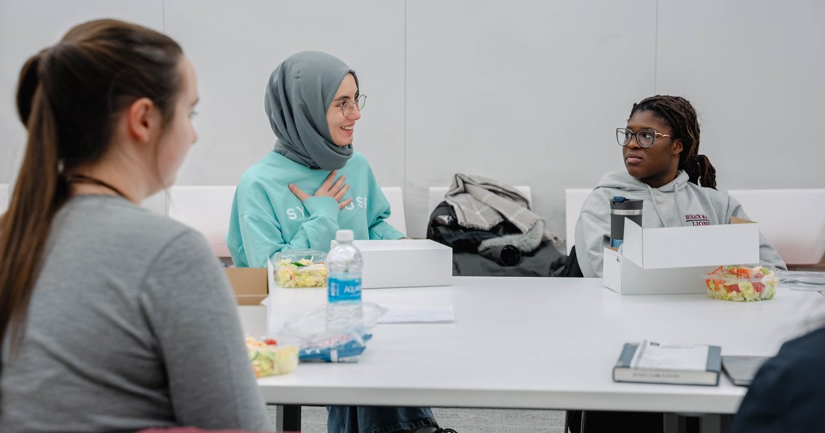 three students sitting at table talking
