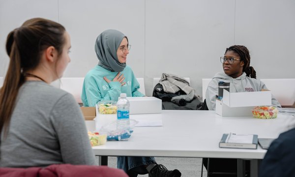 three students sitting at table talking