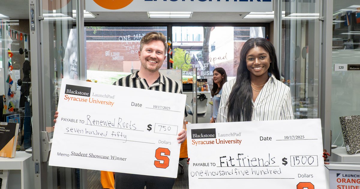 two people holding large checks in front of LaunchPad