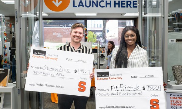 two people holding large checks in front of LaunchPad