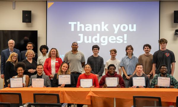group of people posing for photos with screen behind that reads "Thank you judges"