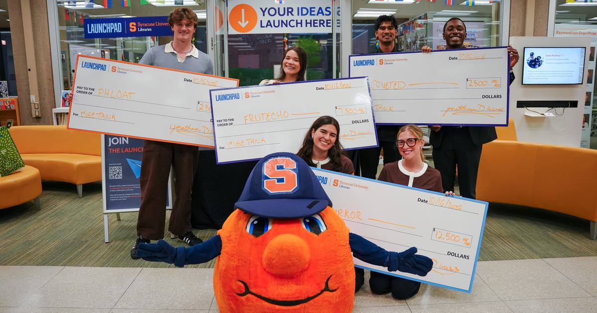 students standing with oversize checks and Otto Orange mascot in the middle