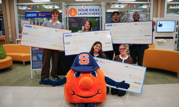 students standing with oversize checks and Otto Orange mascot in the middle
