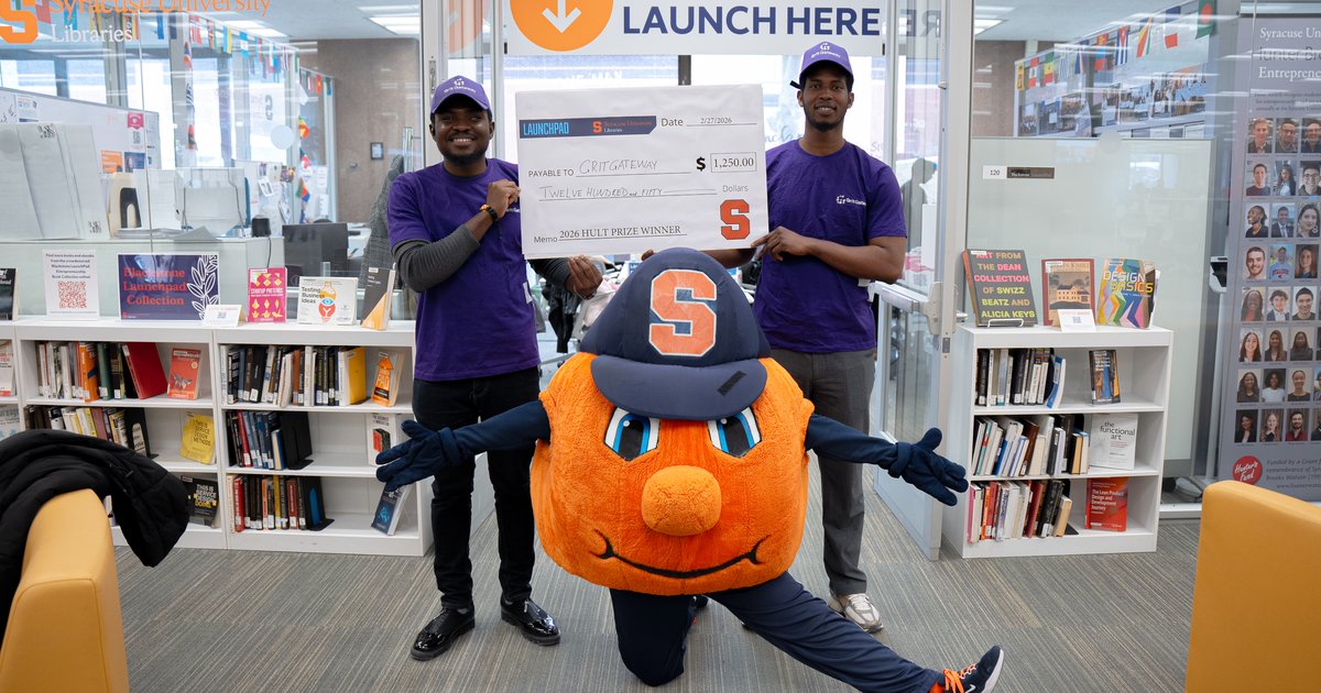 two students holding oversize check with Otto in the middle