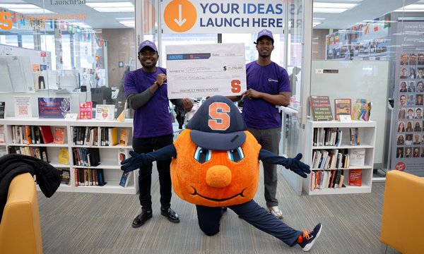two students holding oversize check with Otto in the middle