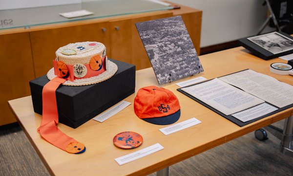 A selection of hats, pins, photographs, and documents arranged on a table.