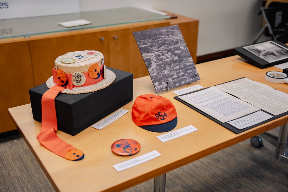 A selection of hats, pins, photographs, and documents arranged on a table.