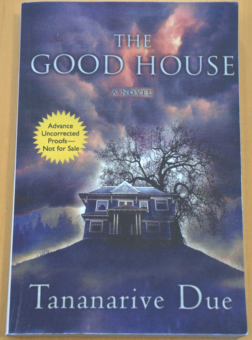 Cover of The Good House by Tananarive Due with blue stormy sky and haunted house with tree on a hill