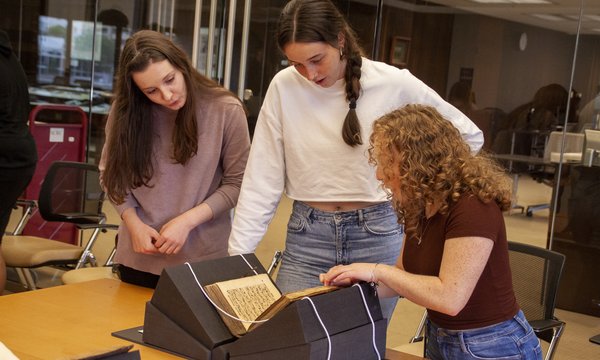 three people looking at antique book