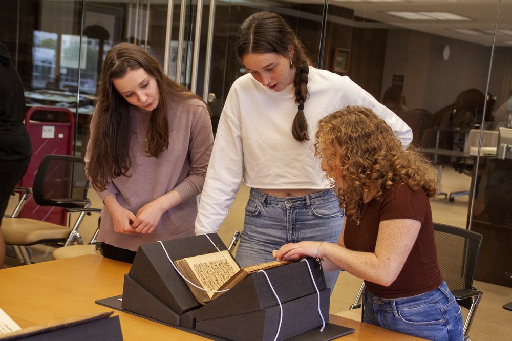 three people looking at antique book