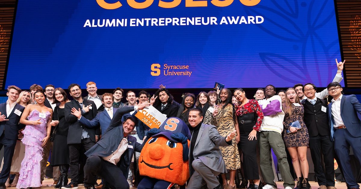 large group of people including Otto the Orange mascot in center with 'CUSE50 banner behind them