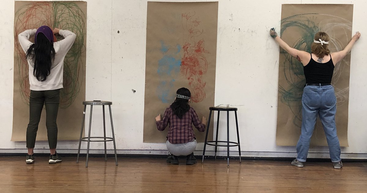 three students posing in front of brown paper on the wall