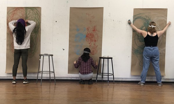 three students posing in front of brown paper on the wall