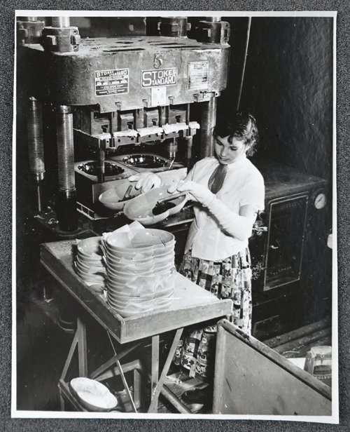 A worker operates a 200-pound press to create vegetable dishes. Edward Hellmich Papers.
