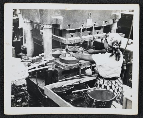 A worker uses a press to make dinner plates. Edward Hellmich Papers.