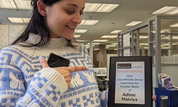 woman with dark hair holding and pointing to plaque with her name