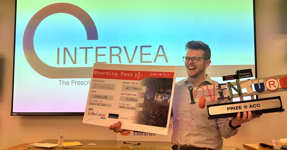 person holding trophy and poster in front of screen that says "Intervea"