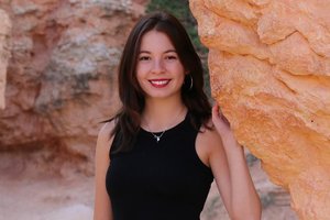 Student posing in front of a scenic cave