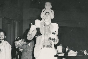 boy on shoulders of young man with other people around