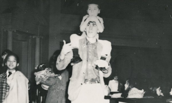 boy on shoulders of young man with other people around