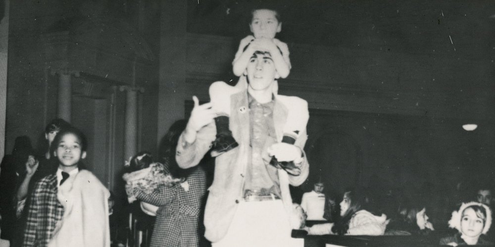 boy on shoulders of young man with other people around