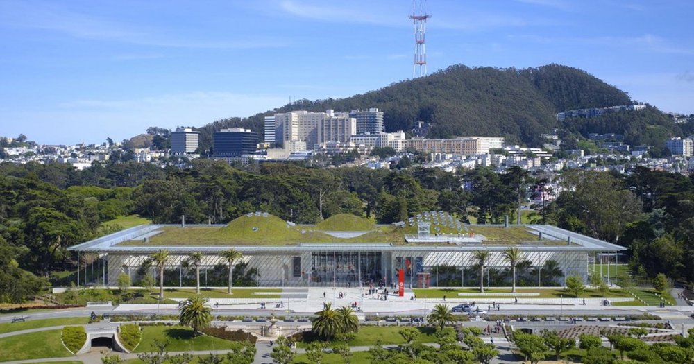 Photo from California Academy of Sciences. Landscape with green trees in foreground, mountains and town in background.
