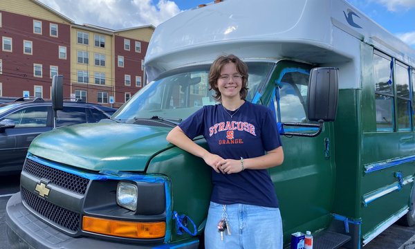 person wearing SU shirt next to green bux