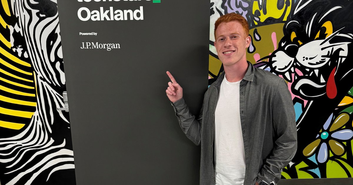 man standing and pointing to sign that says Techstars Oakland