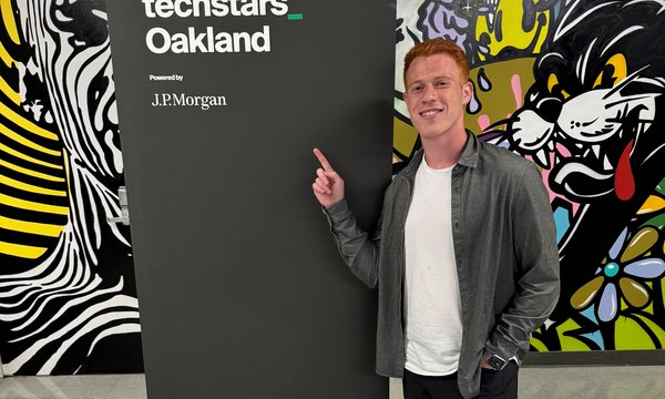 man standing and pointing to sign that says Techstars Oakland
