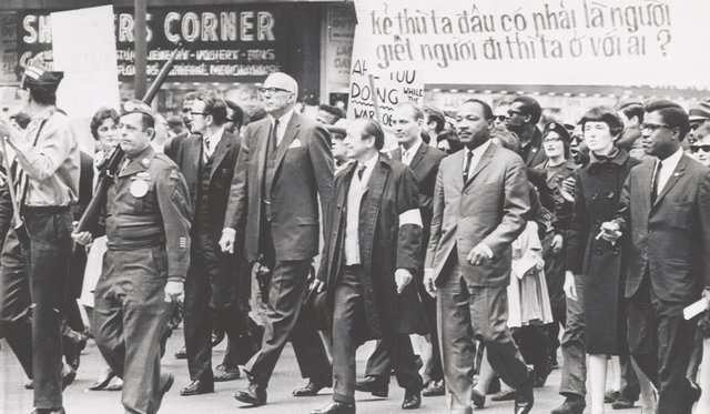 Black and white archival image of large group of people walking together and holding signs