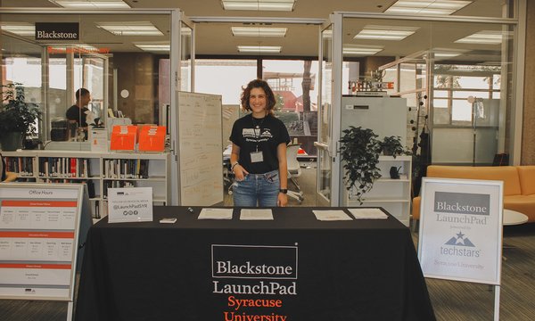 person wearing LaunchPad t-shirt standing in front of table with LaunchPad logo in front of LaunchPad