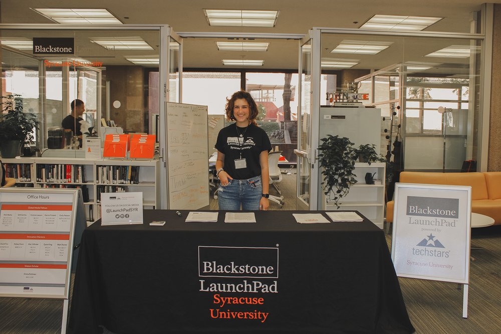 person wearing LaunchPad t-shirt standing in front of table with LaunchPad logo in front of LaunchPad