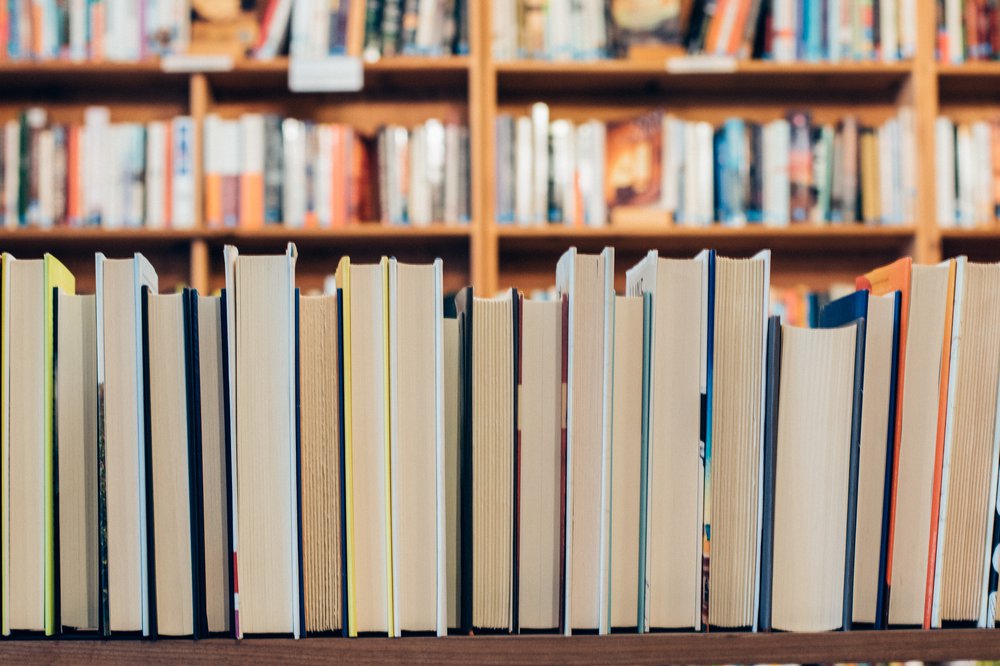 Shelves of books with front row's spines facing away from the camera