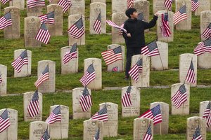 boy in cemetery with flags in front of graves