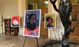 Women's History Month posters and glass book shelf in entry way of Carnegie Library with bronze statue