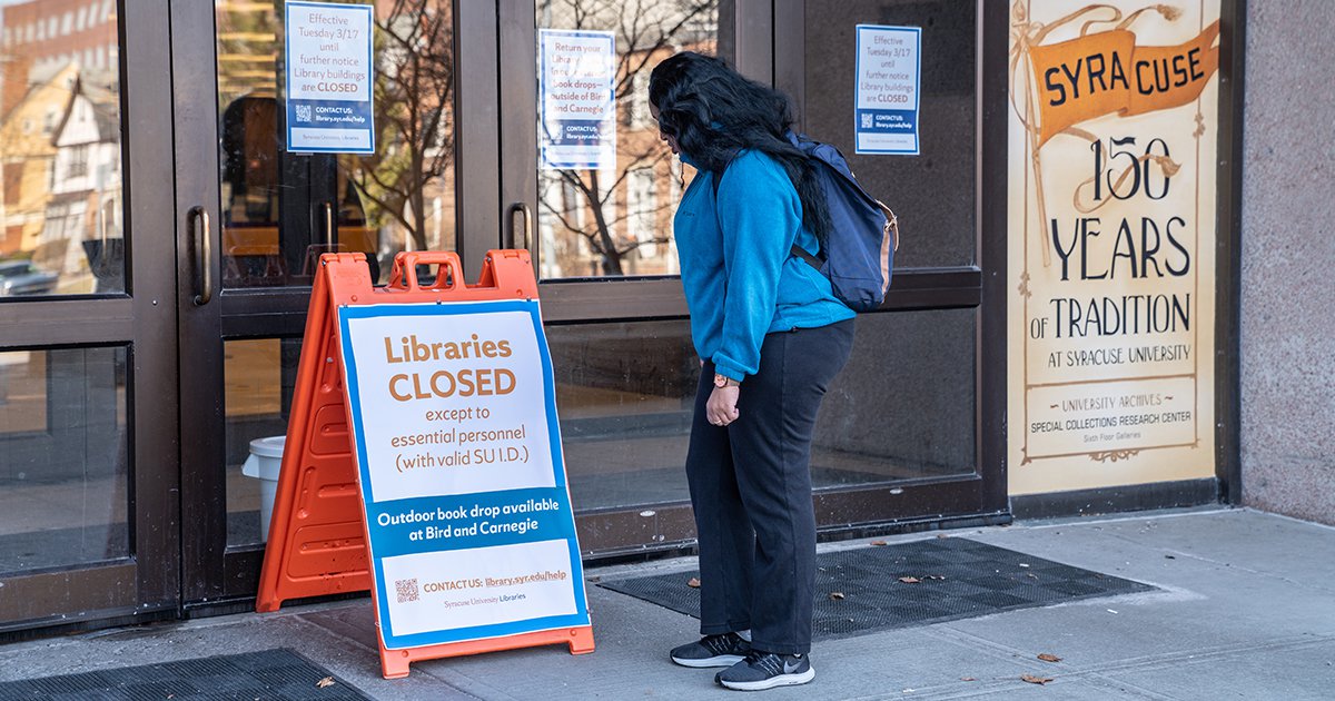 Woman reading sign outside Bird Library that says Libraries Closed during March 2020 COVID 19 pandemic
