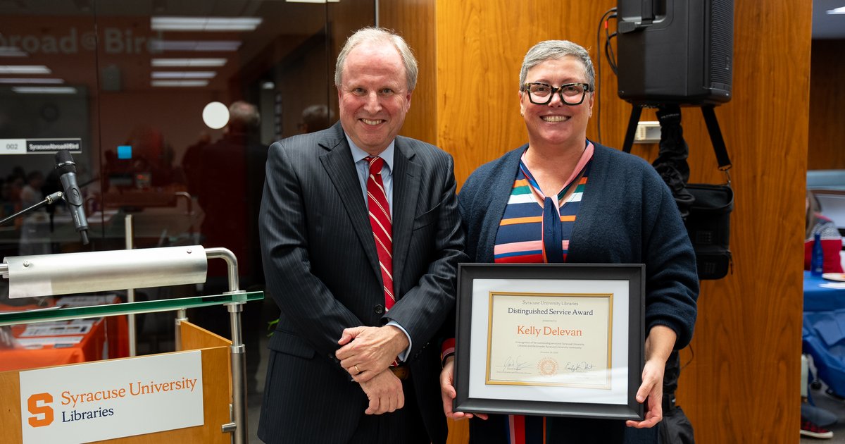 two people standing side by side, with one holding plaque