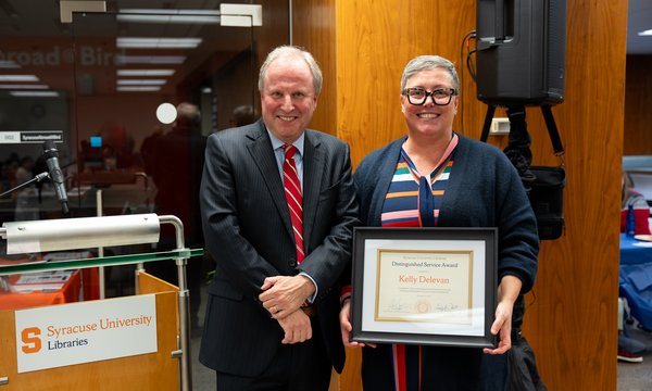 two people standing side by side, with one holding plaque