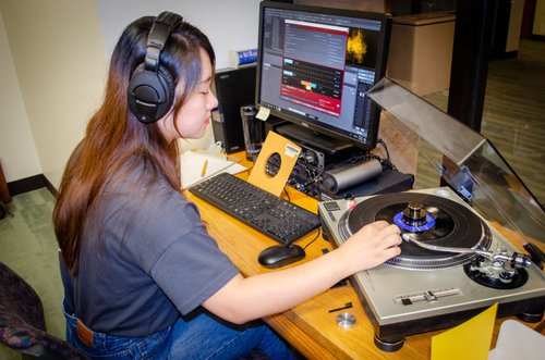 Graduate student sitting at computer next to a record machine