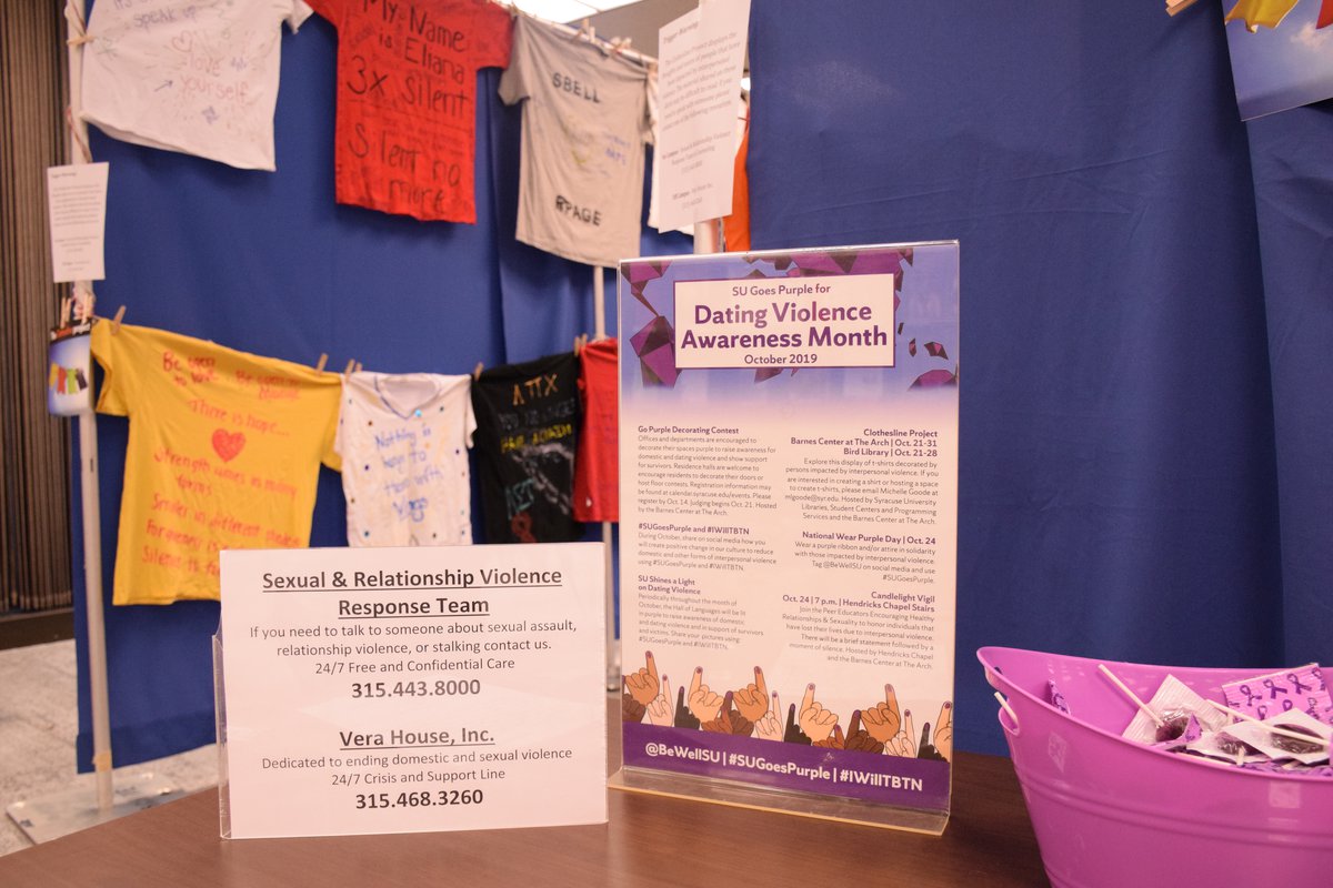 t-shirts hanging on curtain and information displayed on table for "Clothesline Project" - an installation promoting awareness of domestic violence