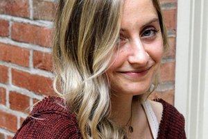young woman in front of a brick wall
