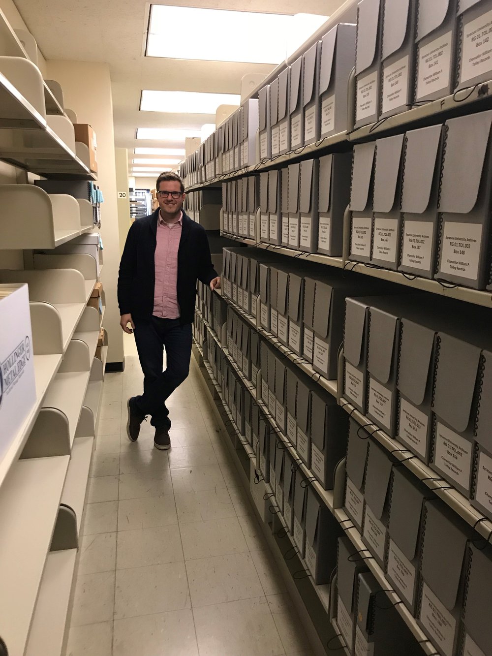 man standing in aisle with shelves of boxes to the right