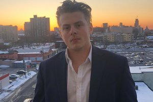 man pose for a photo with buildings and sunset in the background