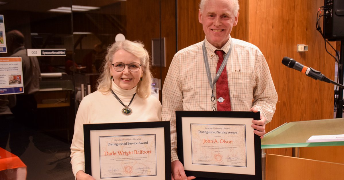 two people standing side by side holding plaques